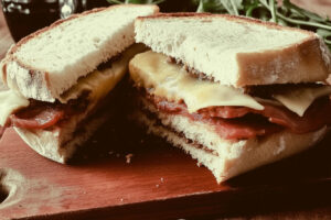 A hearty ploughman’s sandwich with fresh bread, cheese, cold cuts, pickles, and greens, perfect for a satisfying lunch.